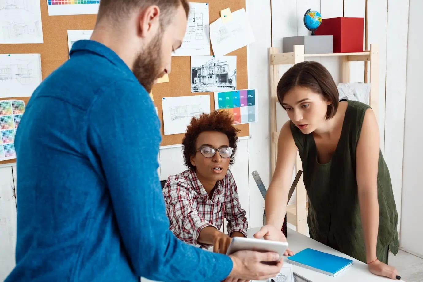 В офисе коллеги рассматривают планшет и обсуждают новые идеи.