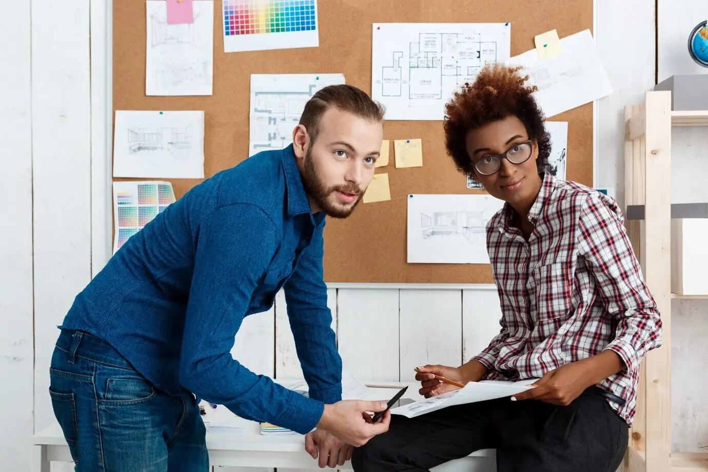 Коллеги улыбаются, разговаривают и обсуждают чертежи и новые идеи.